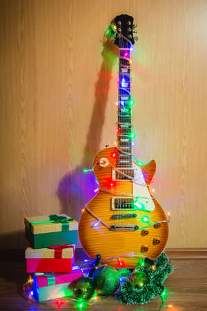 Christmas guitar, guitar dress up in a garland with colored lights close up, new year, Christmas, rock, jazz, Blues, rock-n-roll new year, music, boxes with gifts, Christmas tree decorationsの写真素材