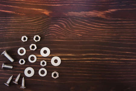 nuts, washers and bolts on brown wood backgroundの写真素材