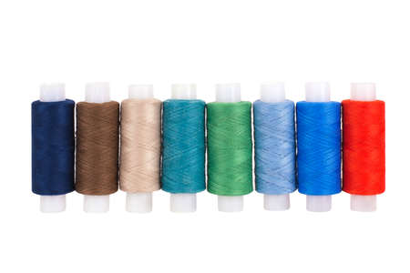 Multi-colored sewing reels stand in a row on a white background, isolated