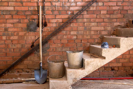 stairs in the house under construction, bucket, shovel, unfinished house from the insideの写真素材