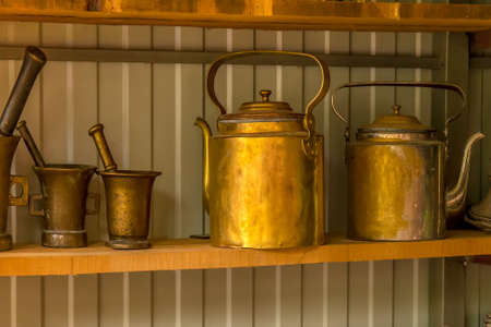 Copper antique teapots and mortars are on the shelf