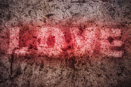 Spray paint in red letters the word love on a dirty wall. The grunge style.