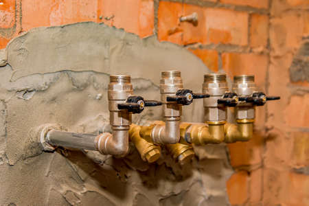 Iron taps with a black handle for supplying water in a brick wall of a residential or public building .の写真素材