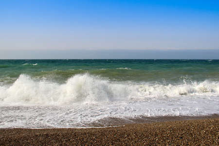 Spray from waves breaking on the beach at seaの写真素材