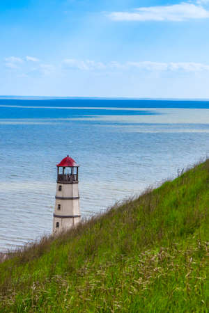 View from behind the green hill to the lighthouse and the seaの写真素材