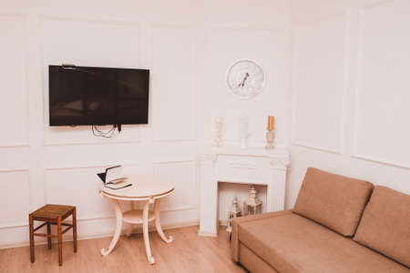 Interior of the room with white walls. Table, sofa, TV and fireplace in the room
