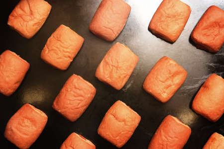 Top view of freshly baked buns on a black baking sheetの写真素材