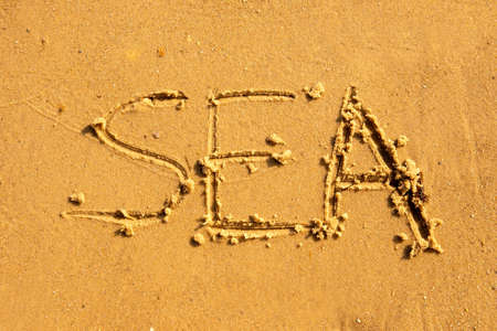 The inscription on the sand is the sea. The word sea is written on the stoveの写真素材