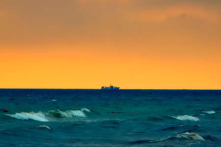 The ship sails in a stormy sea against a yellow skyの写真素材