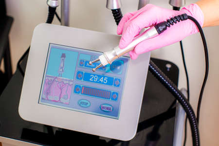 A hand in a rubber glove and a cosmetology device. beauty industry