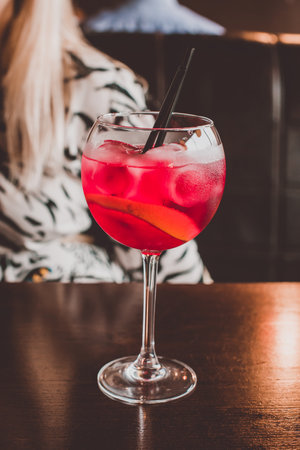 Red cocktail with a straw on the table in the barの写真素材