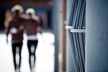 Shot of a metal fence with people walking outside
