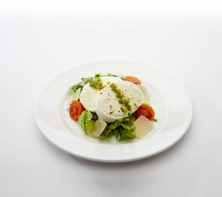 Plate of buffalo mozzarella with summer garden salad on white background