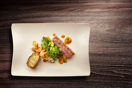 Directly above shot of a stylish Nouvelle cuisine plate of pate with salad and bread on wooden...