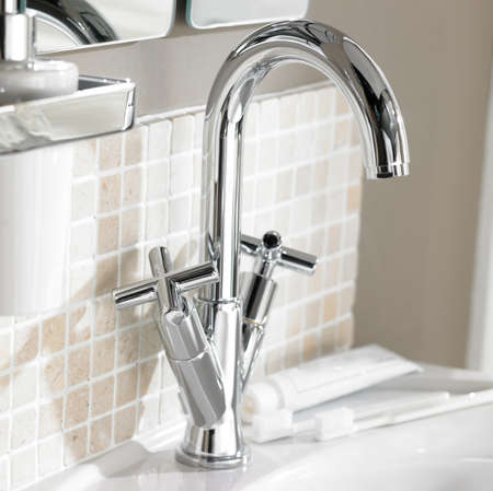 Shot of chrome finish faucet set on washbasin with tiled wallの写真素材