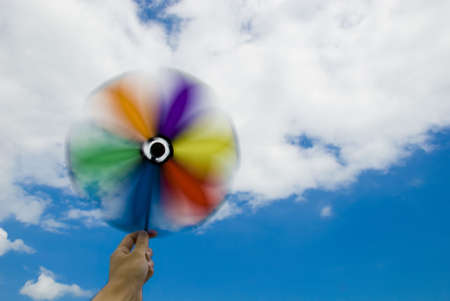 Hand holding spinning wind wheel with cloudy sky の写真素材