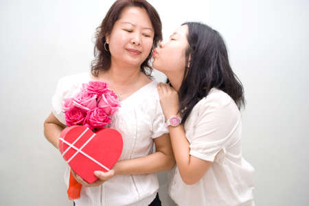 asian girl kissing mum with giftsの写真素材
