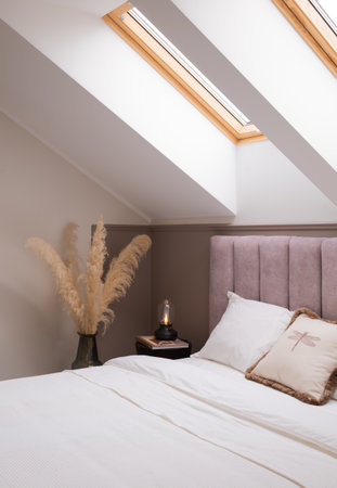 A cozy bedroom with a hardwood bed and skylight in the ceilingの写真素材