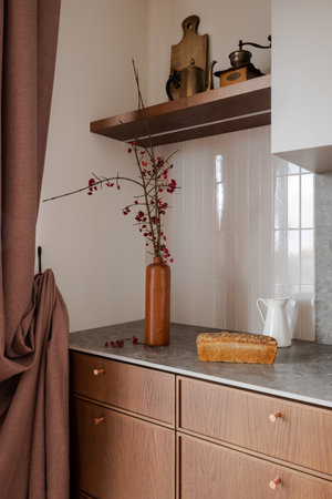 Kitchen counter with loaf of bread and vase of flowers on wood cabinetryの写真素材