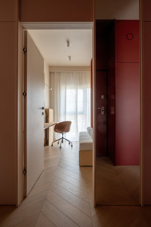 Hallway with hardwood flooring leads to bedroom with desk and chairの写真素材