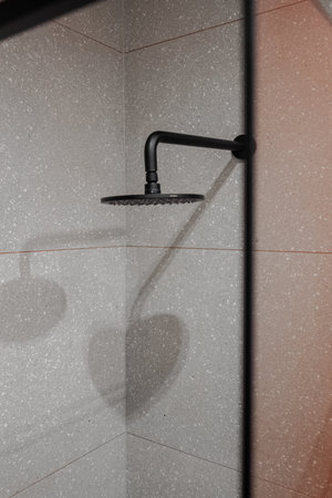 Closeup of a rectangular shower head in monochrome bathroom
