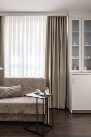 Cozy living room with a wood table by a window, draped in curtain for comfortの写真素材