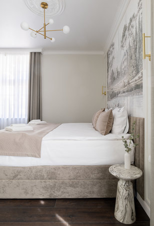 Bedroom furnished with a bed, nightstand, and chandelier for comfort and styleの写真素材