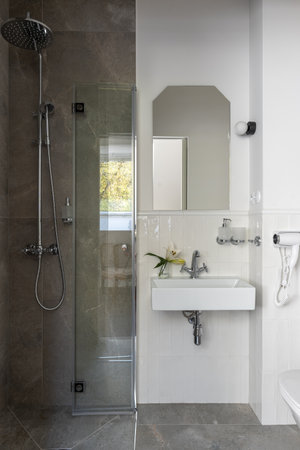 Bathroom with sink, shower, and mirror fixtures in a buildingの写真素材