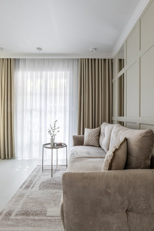 A cozy living room with grey couch, wooden table, and curtains for comfortの写真素材