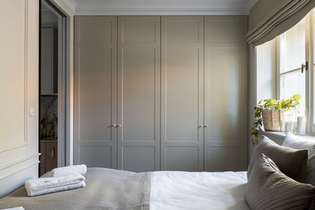 A cozy bedroom with a bed, closets, and a window for comfort and relaxationの写真素材