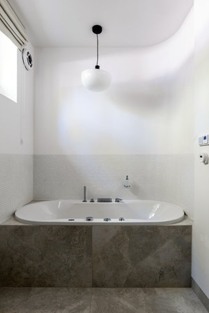 Bathroom with a bathtub and window, featuring plumbing fixture and wood floorの写真素材