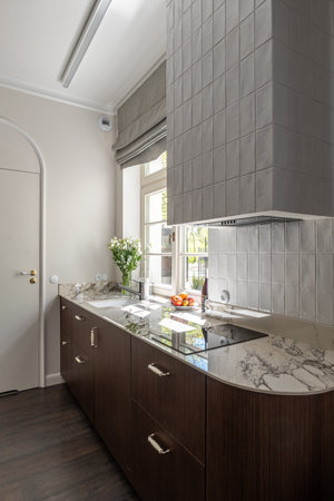 Kitchen with wooden cabinetry, marble countertop, sink, and a windowの写真素材
