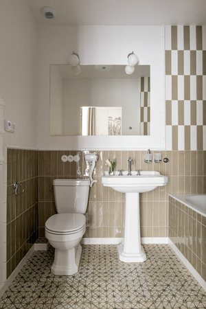 A bathroom with a toilet, sink, mirror, and bathtubの写真素材