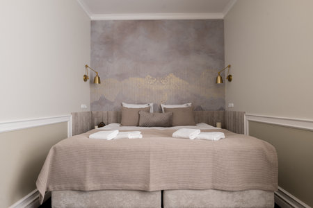 A bed is a fixture in a small bedroom, next to a wallの写真素材