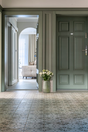 House hallway with a green door and floral vase fixture on wood flooringの写真素材