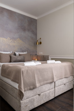 A bedroom with a kingsized bed and a beautiful painting on the wallの写真素材