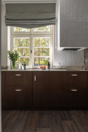 Kitchen features wooden cabinetry, sink, and windowの写真素材