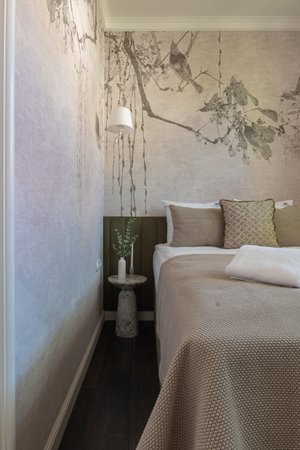 A bedroom with a bed, nightstand, and painting on the wallの写真素材