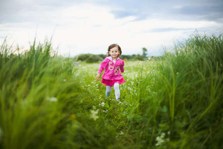 beautiful carefree girl playing outdoors in field with high green grass.freedom conceptの写真素材