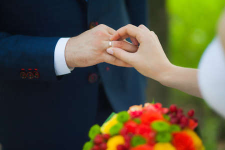 closeup of hands of bridal unrecognizable couple with wedding rings. bride holds wedding bouquet of flowers. exchanging golden rings. love concept. family lifestyleの写真素材