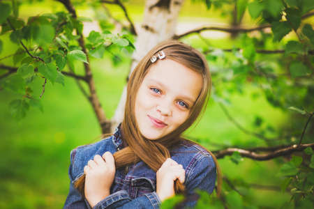 portrait of pretty teen girl smiling and looking at camera. child in green park. close up of cute 12 years old girlの写真素材