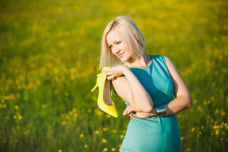 Close up of young  business woman having rest outside after hard day in office. Freedom concept. Free happy girl with shoes off. Lady holds high-heels in hands. Successful people. Spring or summer.の写真素材