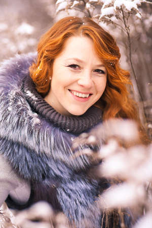 Portrait of beautiful young girl dressed in fur coat at winter trees background. Beauty woman having...