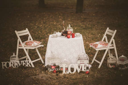 Beautiful photobooth in autumn wood. Decorated chairs and table. Image toned and stylized in retro style.の写真素材