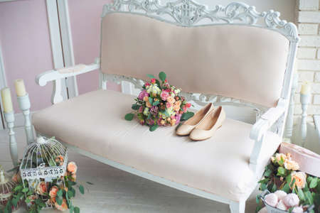 Female shoes and bouquet of flowers on sofa in beautiful interiorの写真素材