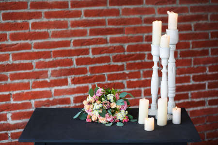 Many old white candles on old black table at red brick wall background.の写真素材