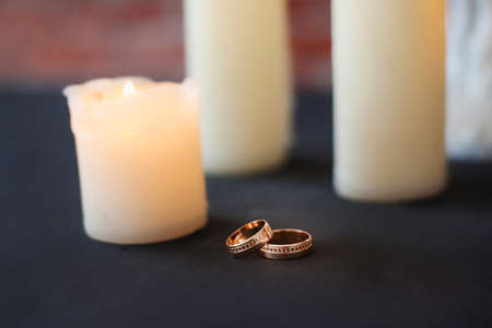 Old white candles on old black table at red brick wall background.の写真素材