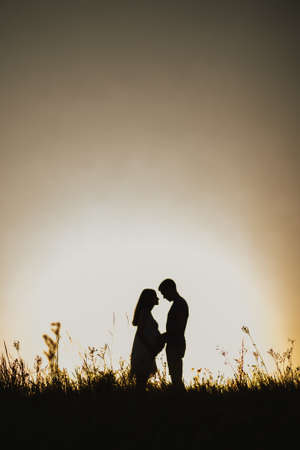Silhouette of pregnant lady and husband. Sunsetの写真素材