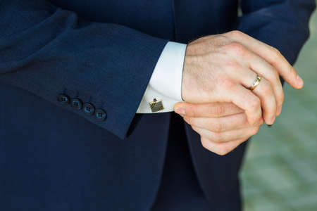 Close-up of elegance male hands. man dressed in blue suit and white shirt. Businessman fixing...