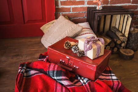Christmas decor. Festively decorated Christmas interior in red and brown colors. Horizontal color image of photo booth with brick brown wall, wooden floor, painted door, pillows, presents.の写真素材